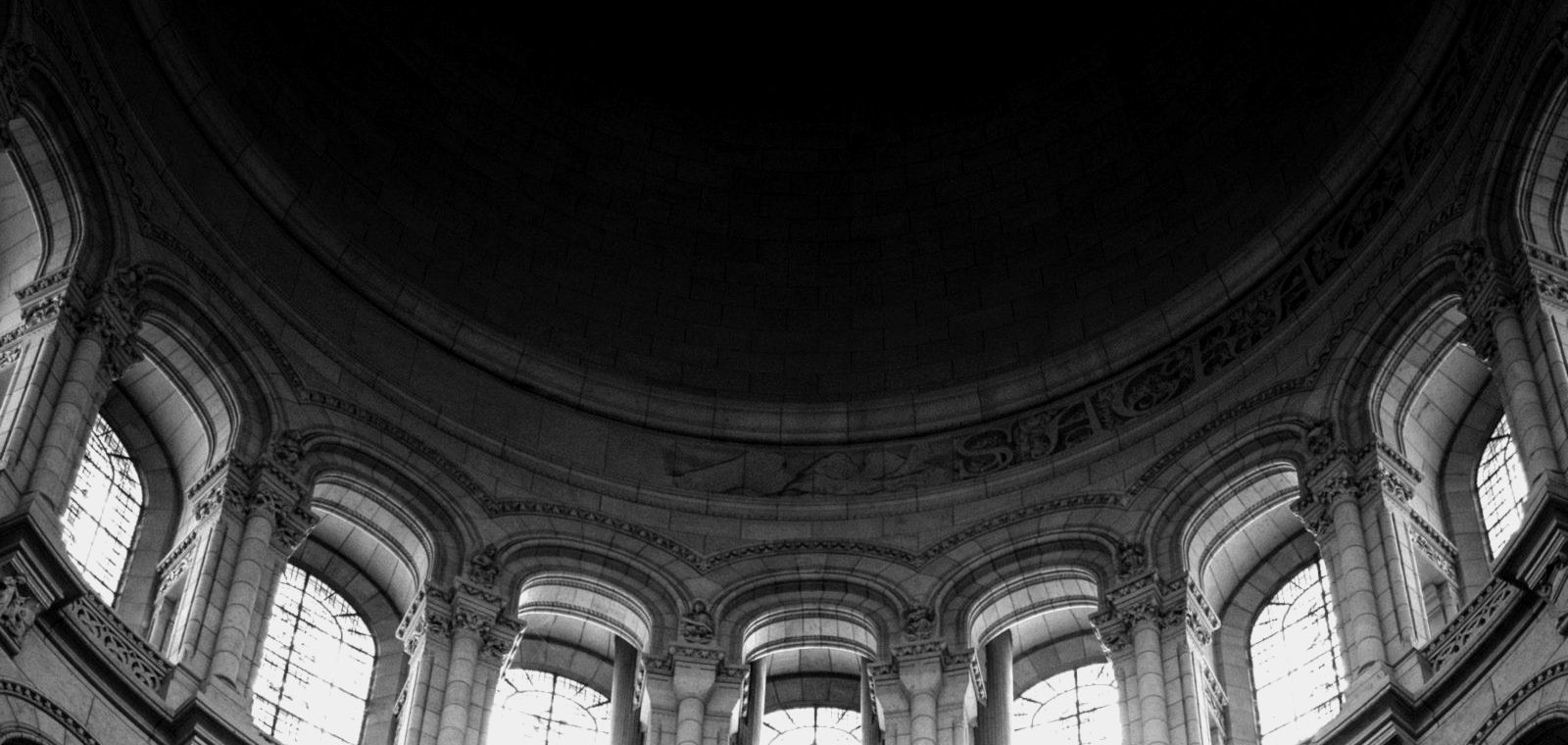 Looking up into a vast dome: one structure carried by many parts, black and white
